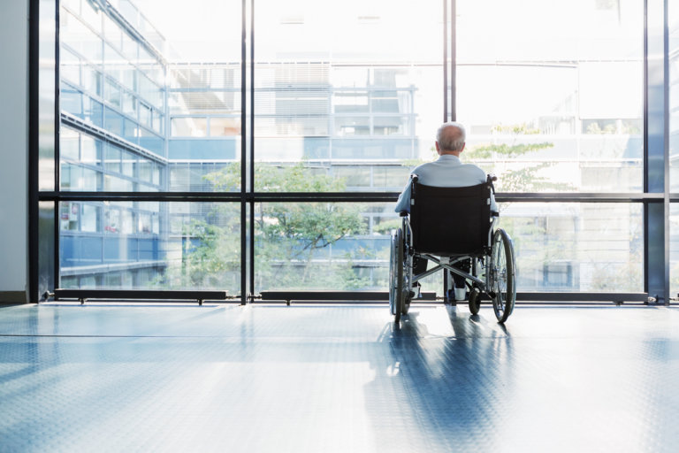 Senior man in a wheelchair in a nursing home, experiencing abuse.