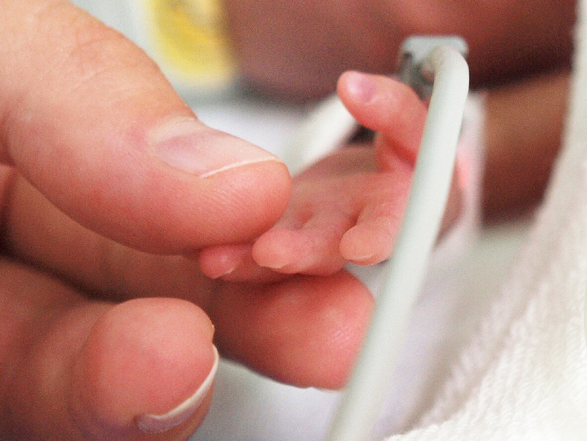 newborn baby holding hand with someone