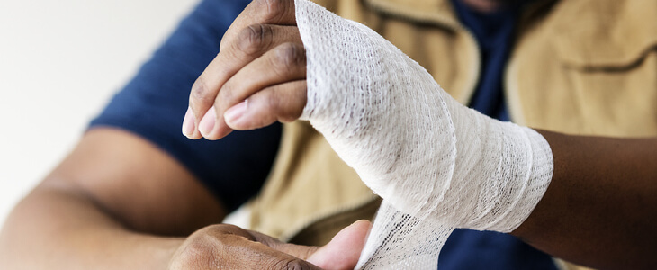 Man bandaging up his own hand from a burn injury