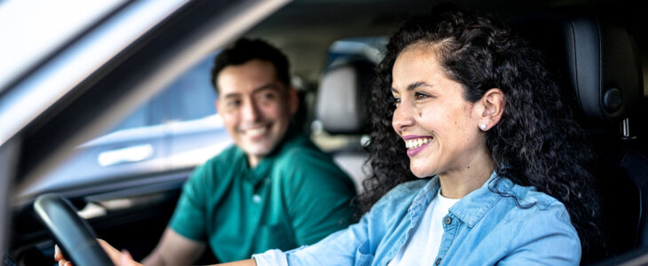 Mid adult woman driving a car with her husband in city